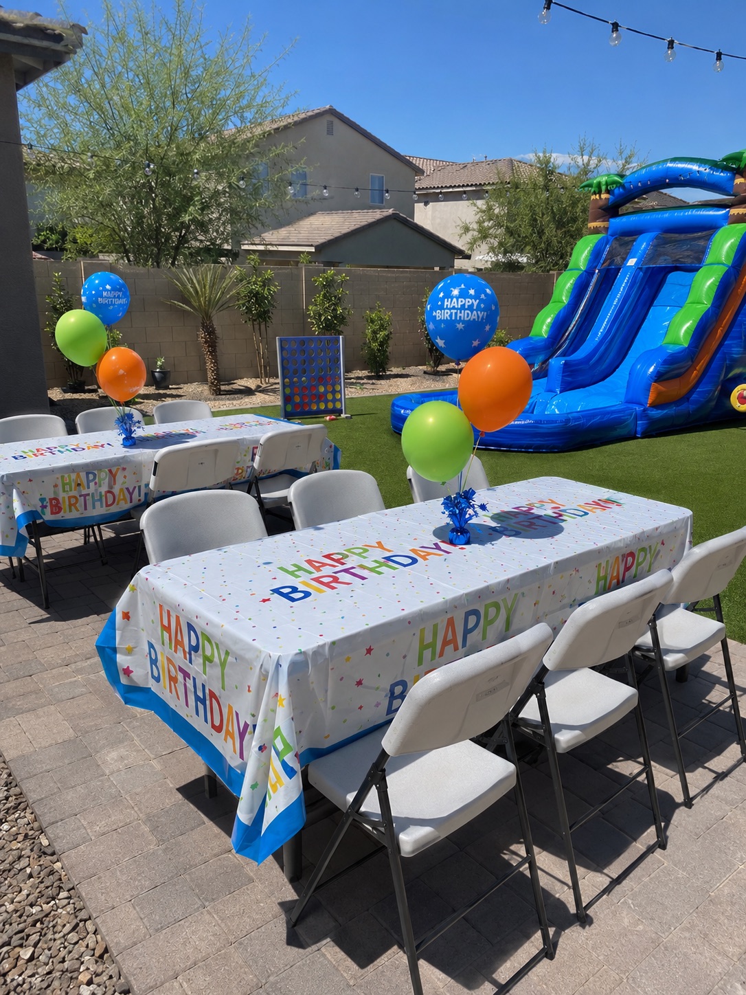 Giant Connect 4 game beside birthday tables and white folding chairs in an Arizona backyard